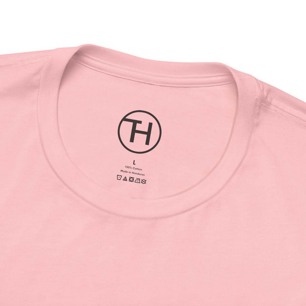 Close-up of the neckline of a light pink cotton t-shirt, showcasing the tag and logo for sizing.