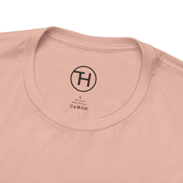 Close-up of a light peach t-shirt collar showing the tag and care instructions, highlighting its soft cotton fabric.